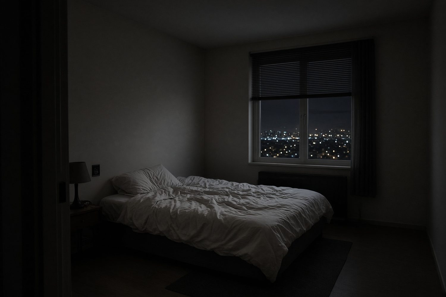 An unmade bed and a window onto city lights.