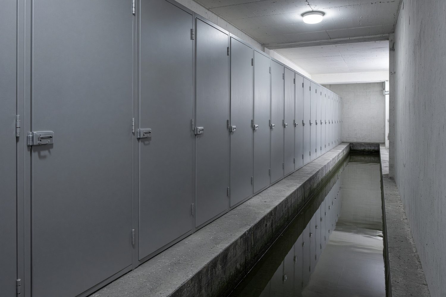Plain metal cabinets beside a channel of still water.