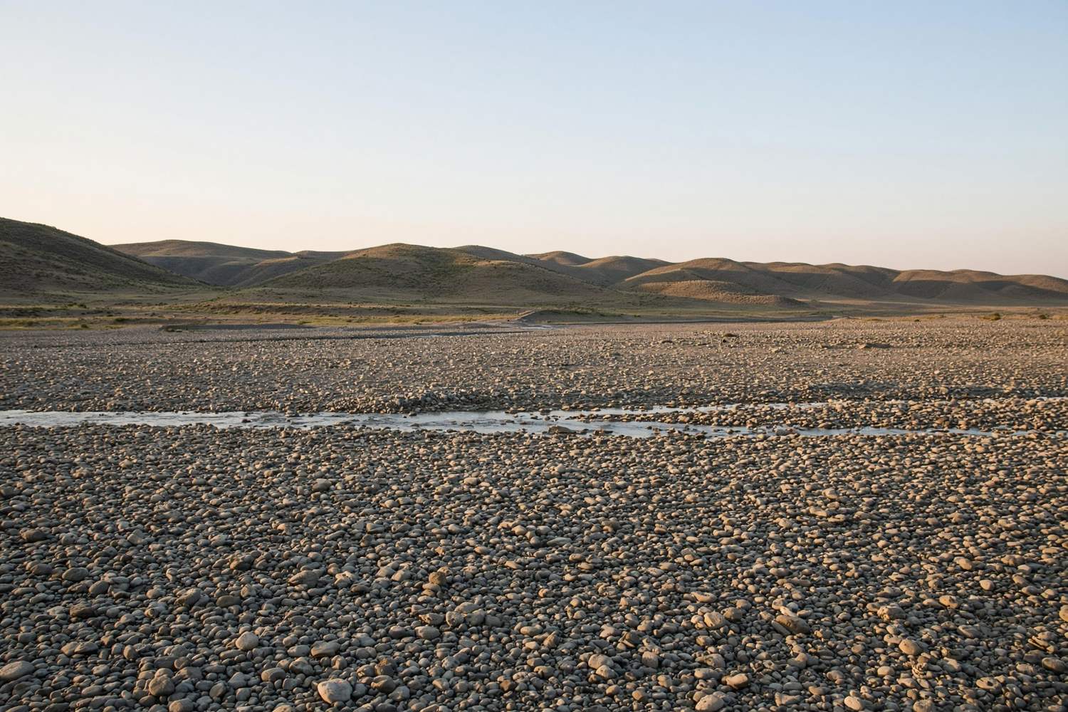 A thin stream across a wide bed of stones.